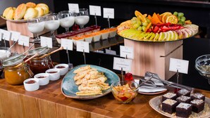 Buffet variado com diversos itens, incluindo doces, frutas e sobremesas.