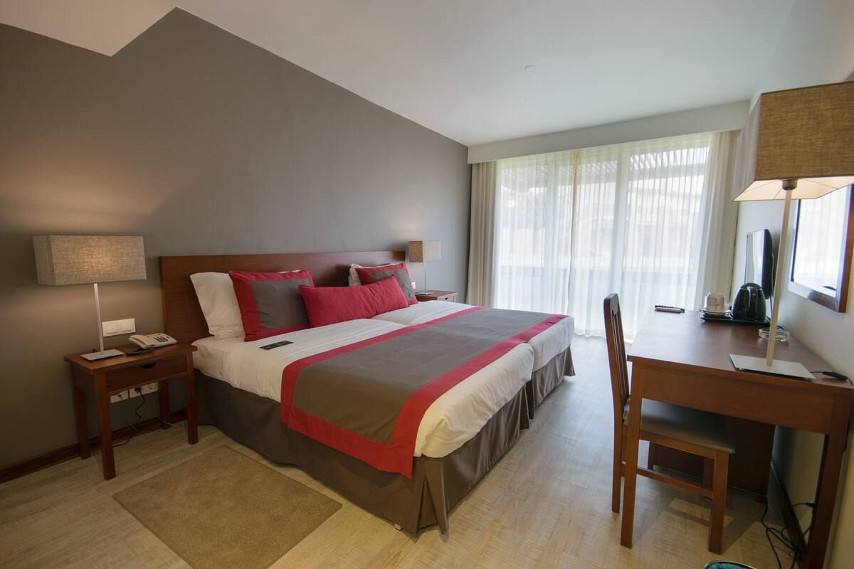 Una habitación de hotel con cama, mesitas de noche, escritorio y una silla.