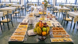 A buffet setup with various food items and utensils. - Hotel Oásis Atlântico Praiamar (Praia)