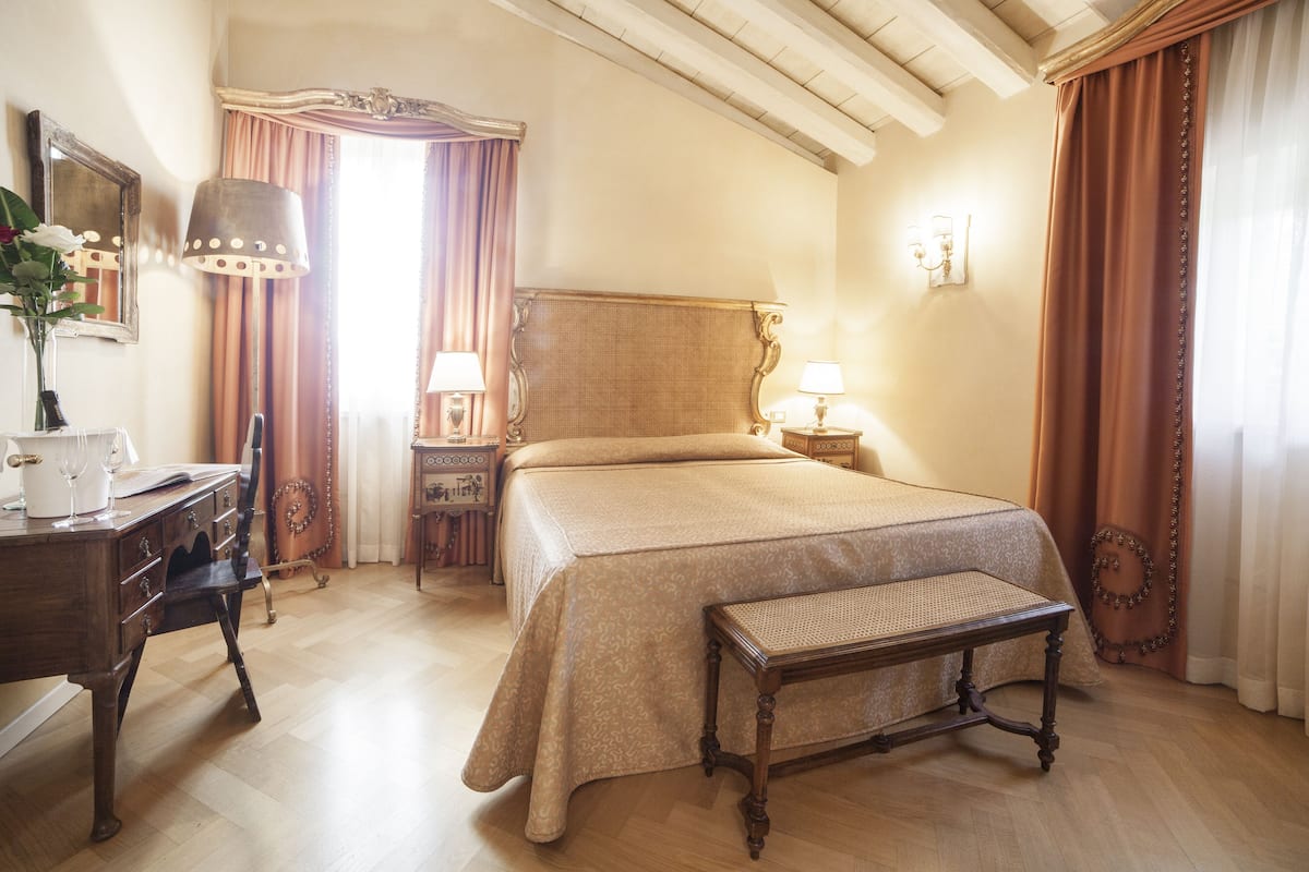 A hotel room with a large bed, wooden furniture, and a classic design.