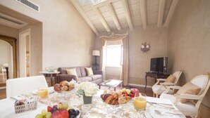 Ein Frühstückstisch für zwei Personen, gedeckt mit Croissants, Früchten und einem Glas Orangensaft.