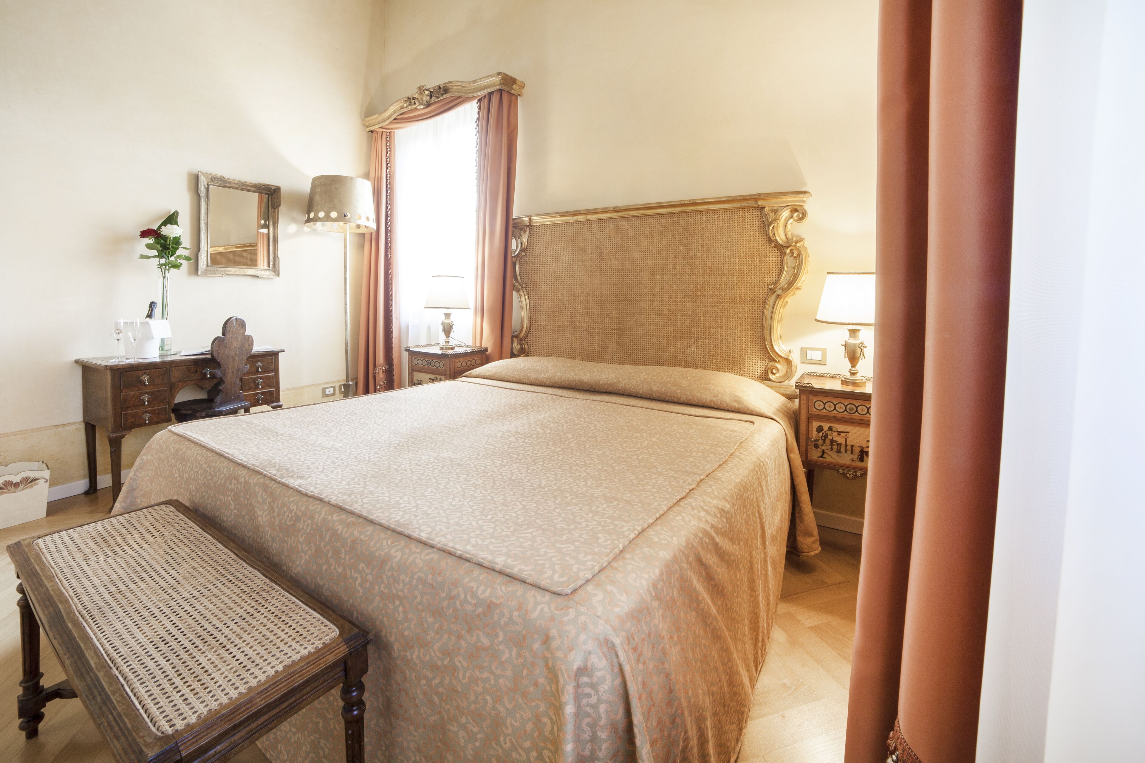 A neatly arranged bedroom with a large bed, a bedside table, a lamp, and a dresser.