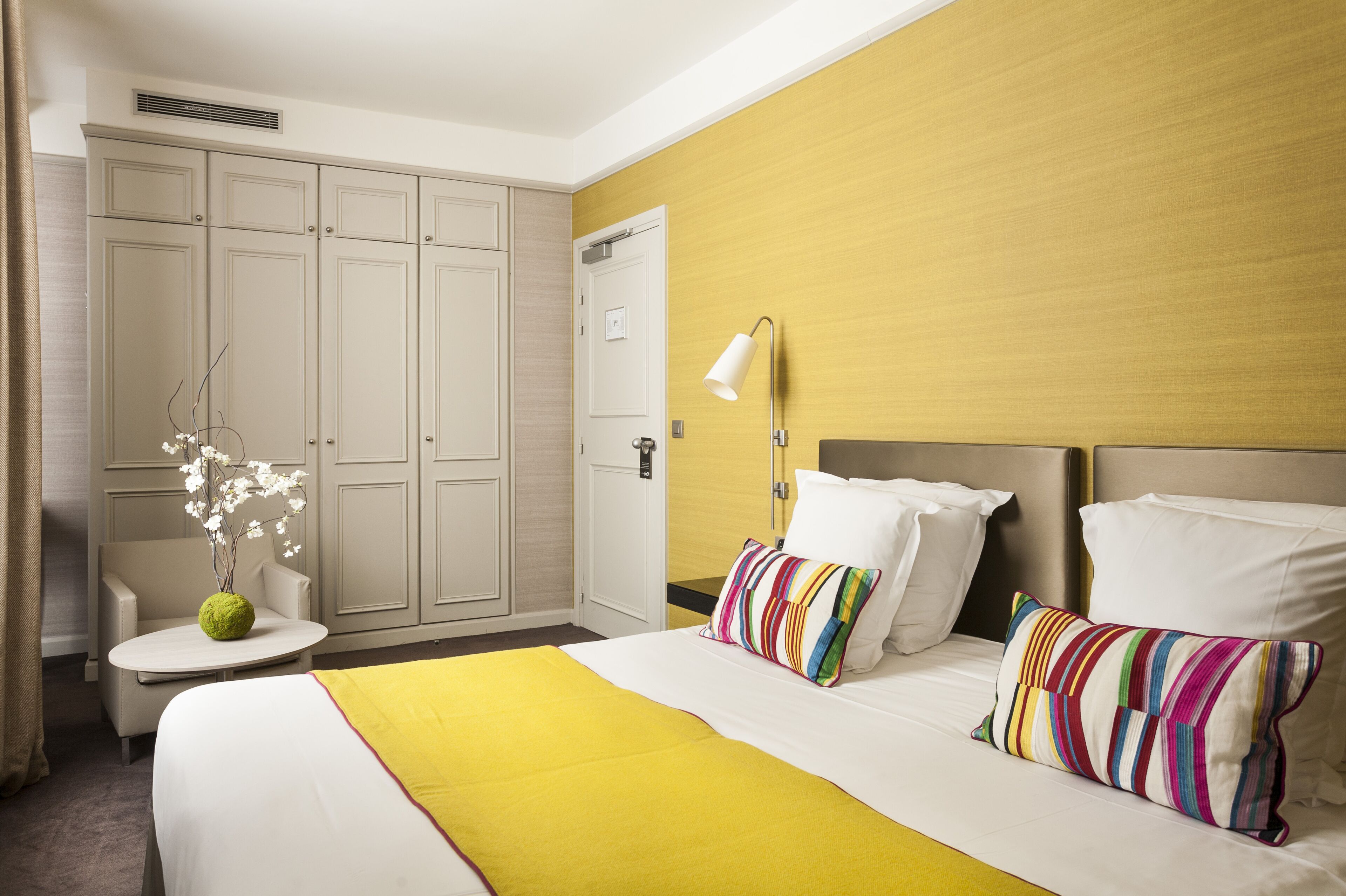 Una habitación de hotel con una cama, una mesita de noche, una silla, una lámpara y un armario.