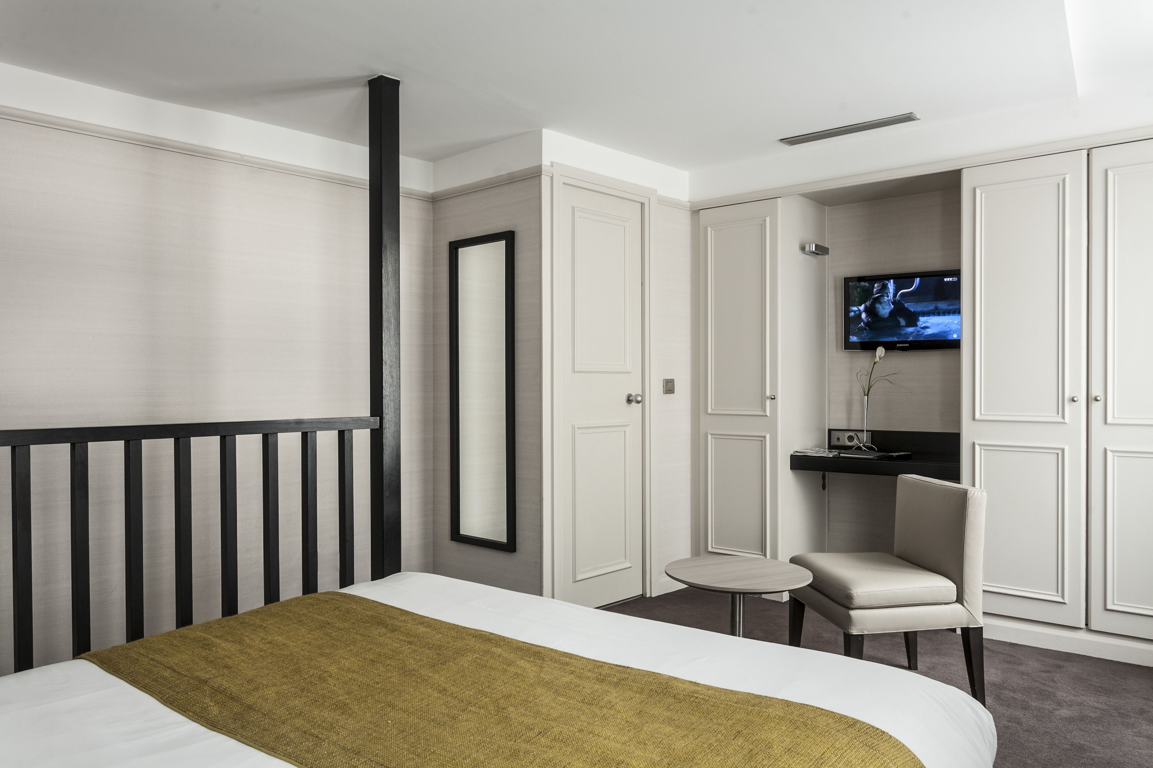 Ein modernes Hotelzimmer mit Bett, Schreibtisch mit Stuhl, Fernseher und Kleiderschrank.