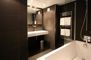 A modern bathroom with a large bathtub, a sink, and a mirror.