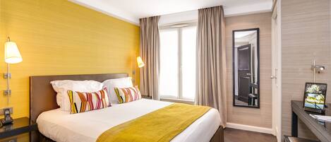A hotel room with a large bed, bedside lamps, a desk, and a mirror.