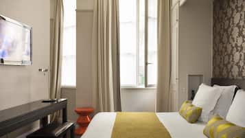 A hotel room with a bed, a desk, a chair, a television, and a window with curtains.