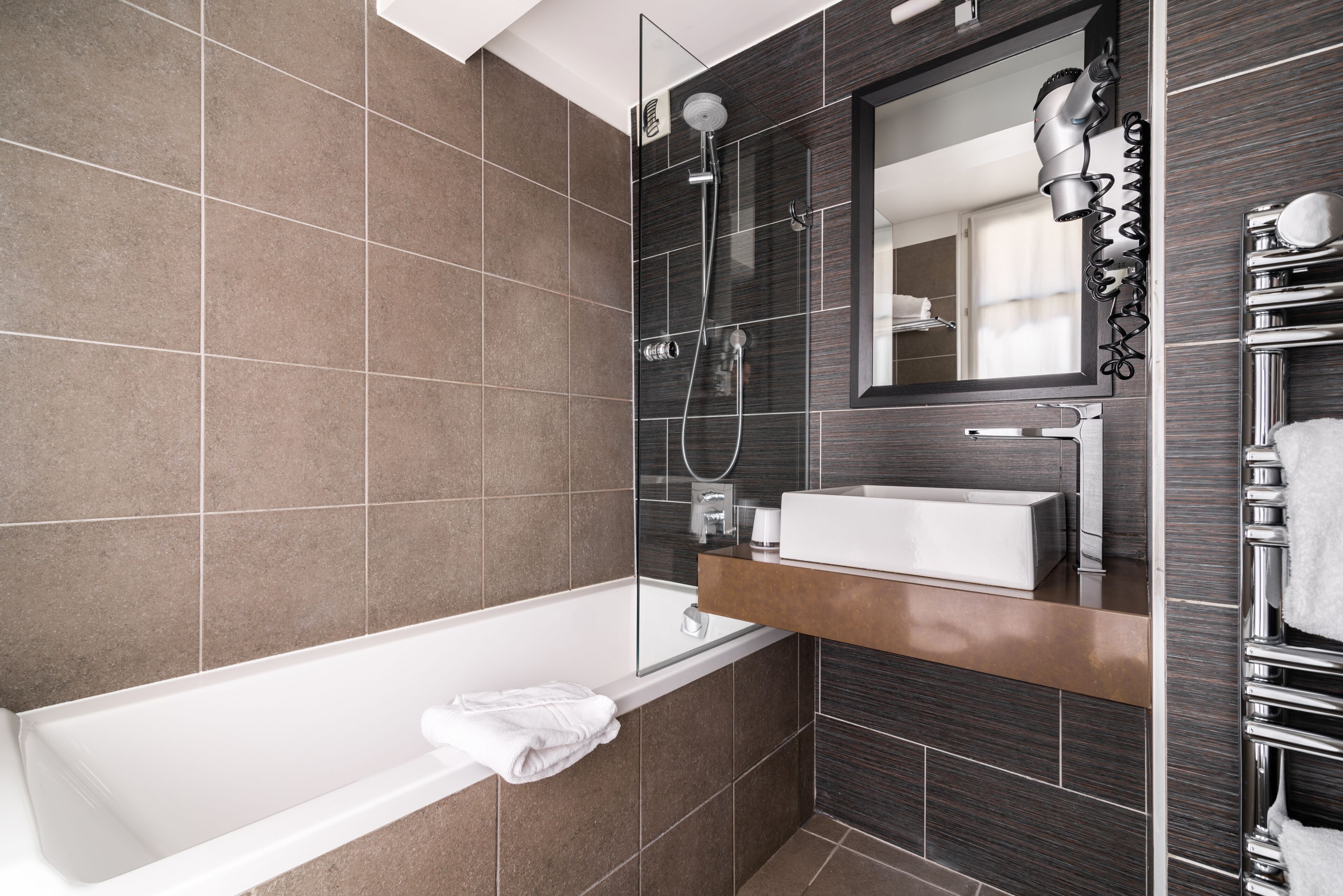 Une salle de bain moderne avec une baignoire, un meuble-lavabo avec un miroir et un espace douche.