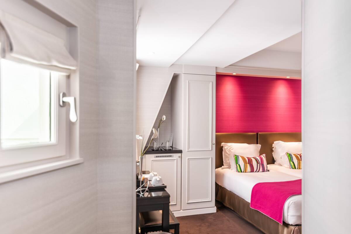 A hotel room with a bed, a desk, and a wardrobe.