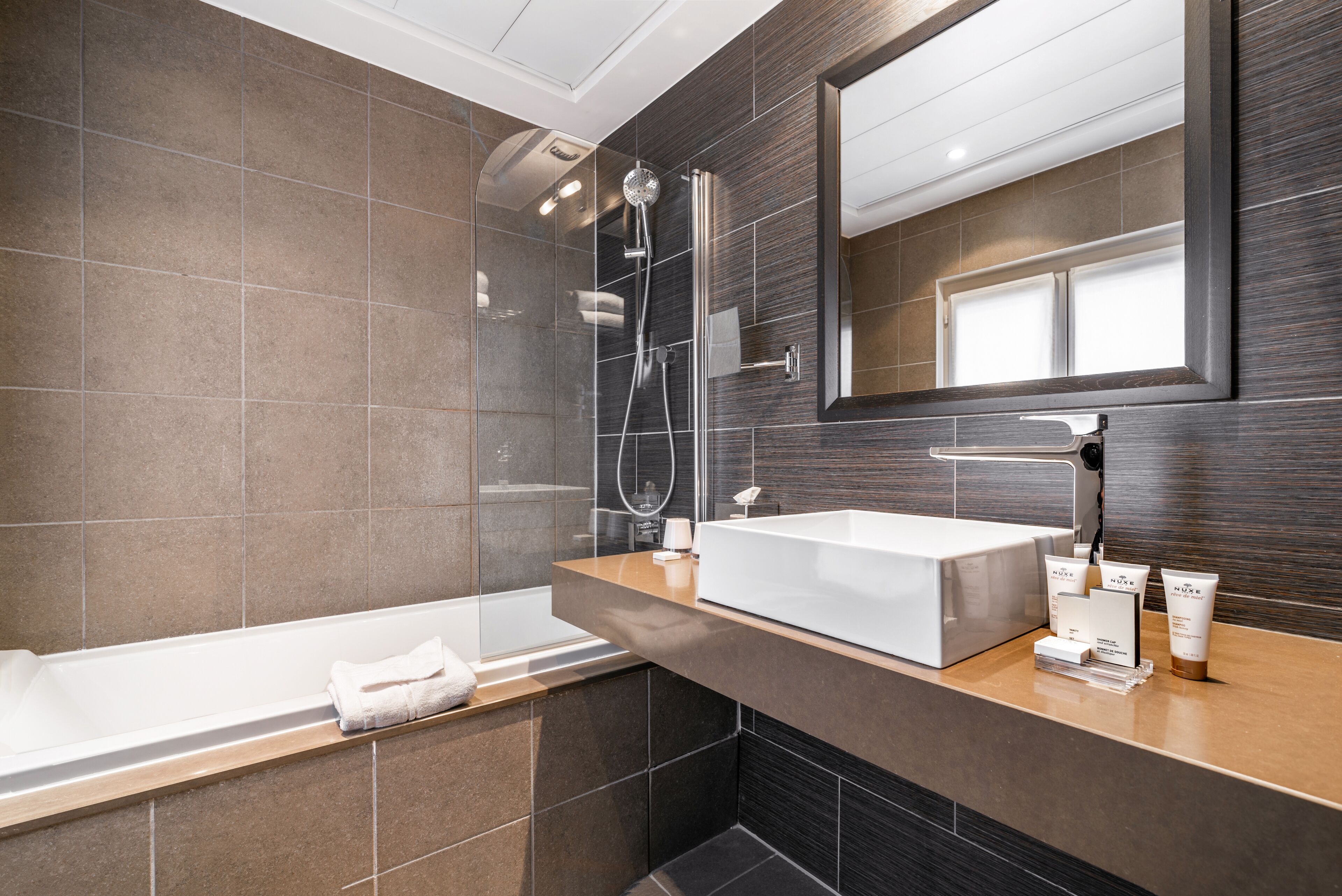 A modern bathroom with a large bathtub, a glass-enclosed shower, and a vanity with toiletries.
