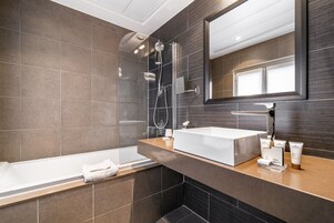 Un bagno moderno con una vasca da bagno ampia, una cabina doccia in vetro e un mobile lavabo con articoli da toilette.