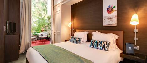 Habitación de hotel con una cama grande, televisión, escritorio con silla y ventana con cortinas.