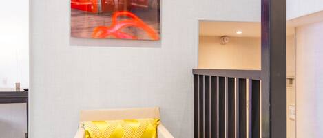 A modern interior with a beige sofa, a red abstract painting, and a dark wooden partition.