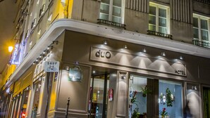 A hotel facade with multiple windows, a sign indicating a bicycle parking area, and a storefront with a sign that reads "HOTEL". - Hotel Duo (Paris)