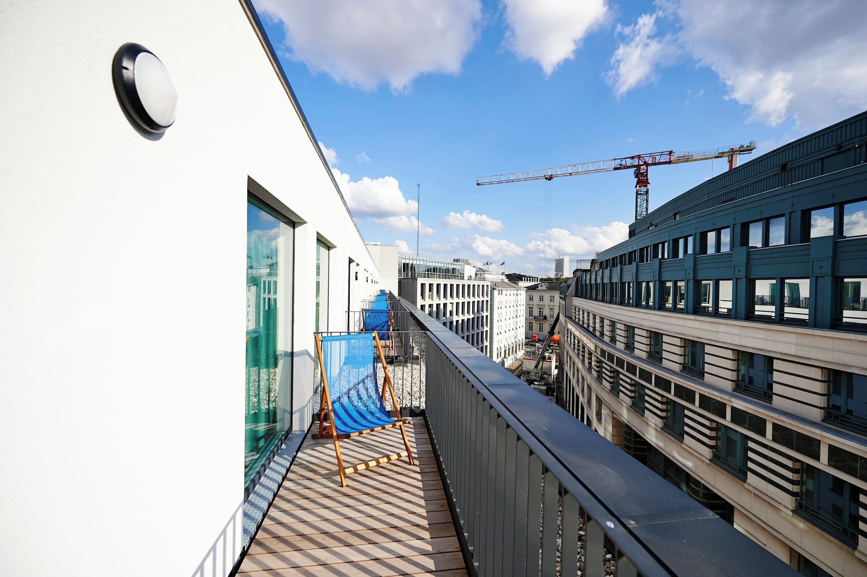 Ein Balkon mit Blick auf eine Baustelle, einen Kran und angrenzende Gebäude.