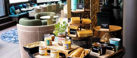 A breakfast buffet with various pastries, jams, and a coffee station.