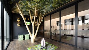 A modern office space with a large glass wall, wooden tree sculpture, and a children's play mat. - Van der Valk Hotel Uden-Veghel (Uden)