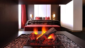 A hotel room with a bed, a fireplace, and two bedside lamps. - Van der Valk Hotel Uden-Veghel (Uden)