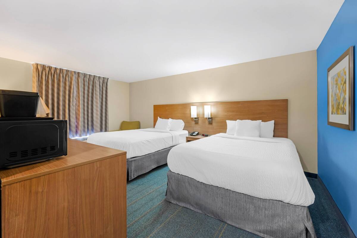 Ein Hotelzimmer mit zwei Betten, einem Schreibtisch mit Fernseher und einem Nachttisch mit Telefon.