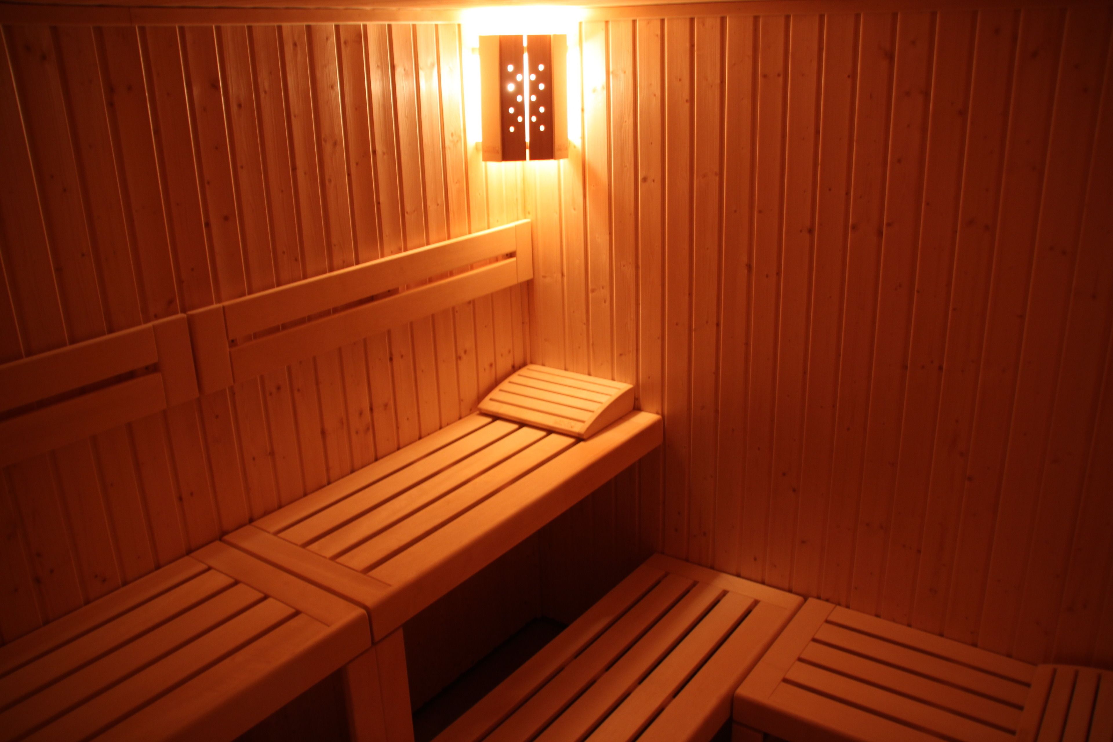 A sauna with wooden benches and a wall-mounted light fixture.