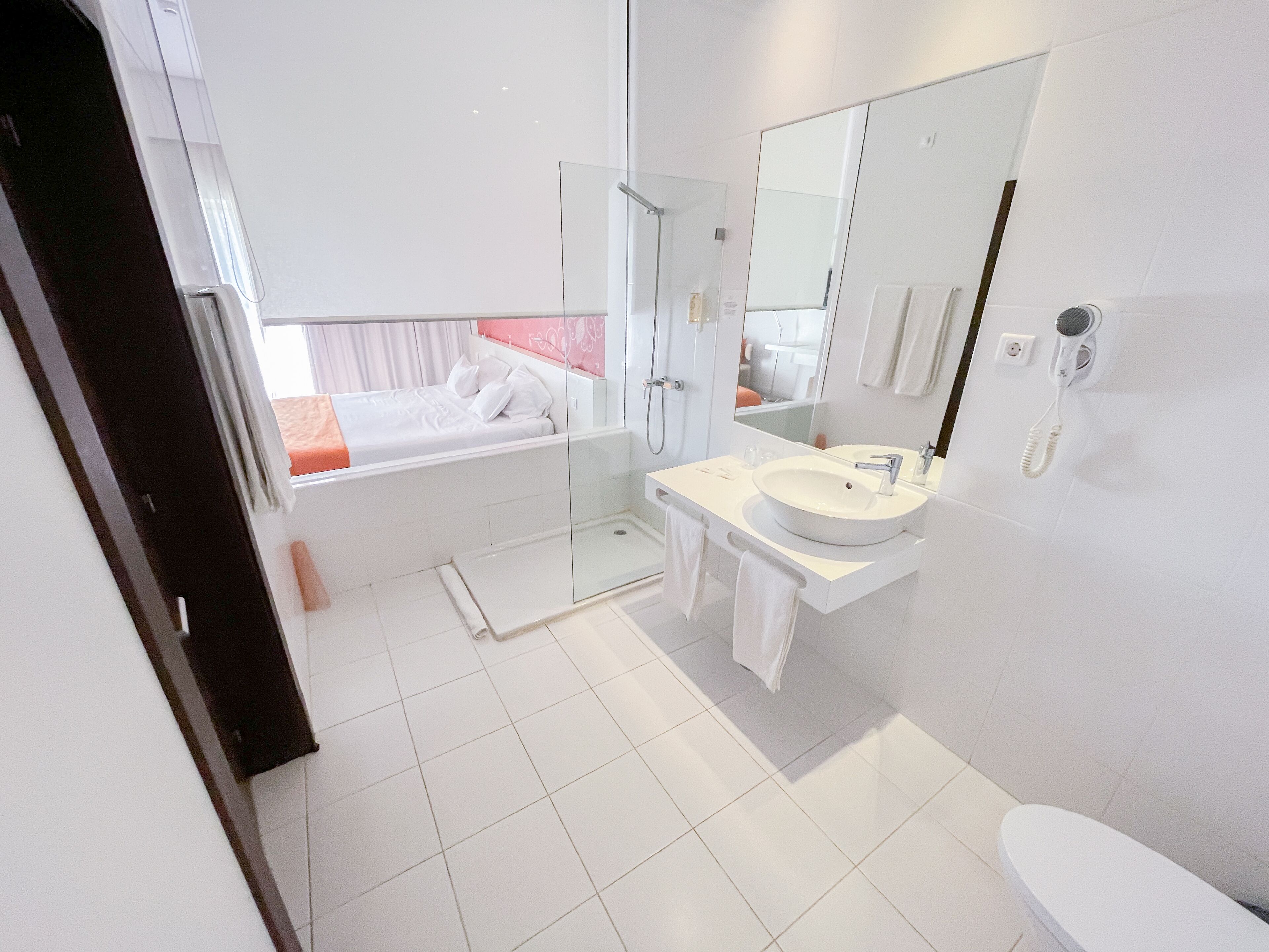 Un baño moderno con cabina de ducha de vidrio, un lavabo blanco y un espejo grande.