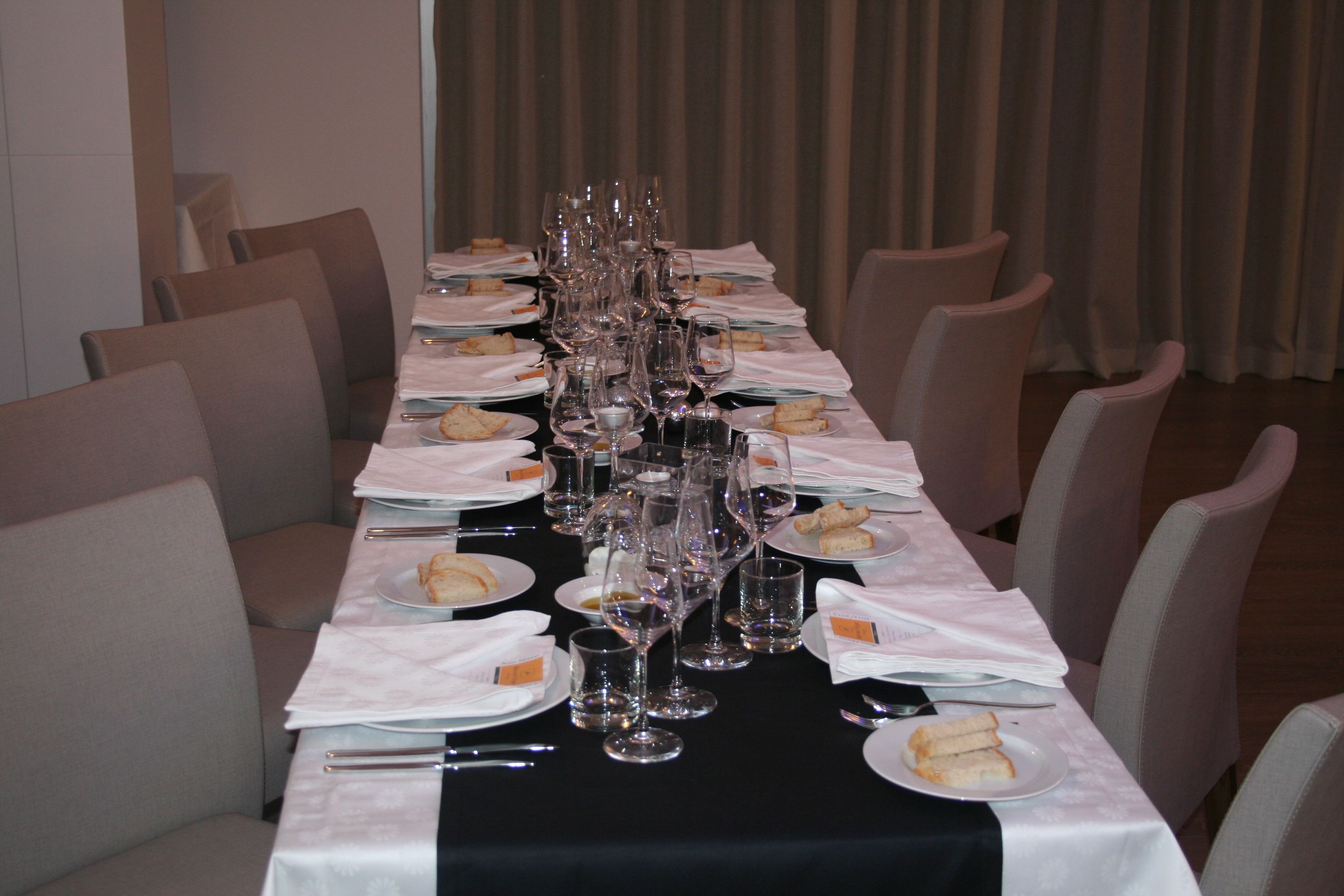 A long dining table set with multiple wine glasses, plates with sandwiches, and cutlery.