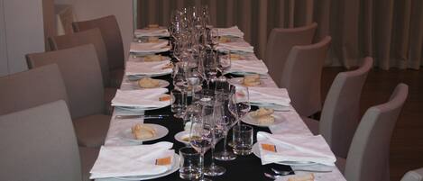 A long dining table set with multiple wine glasses, plates with sandwiches, and cutlery.