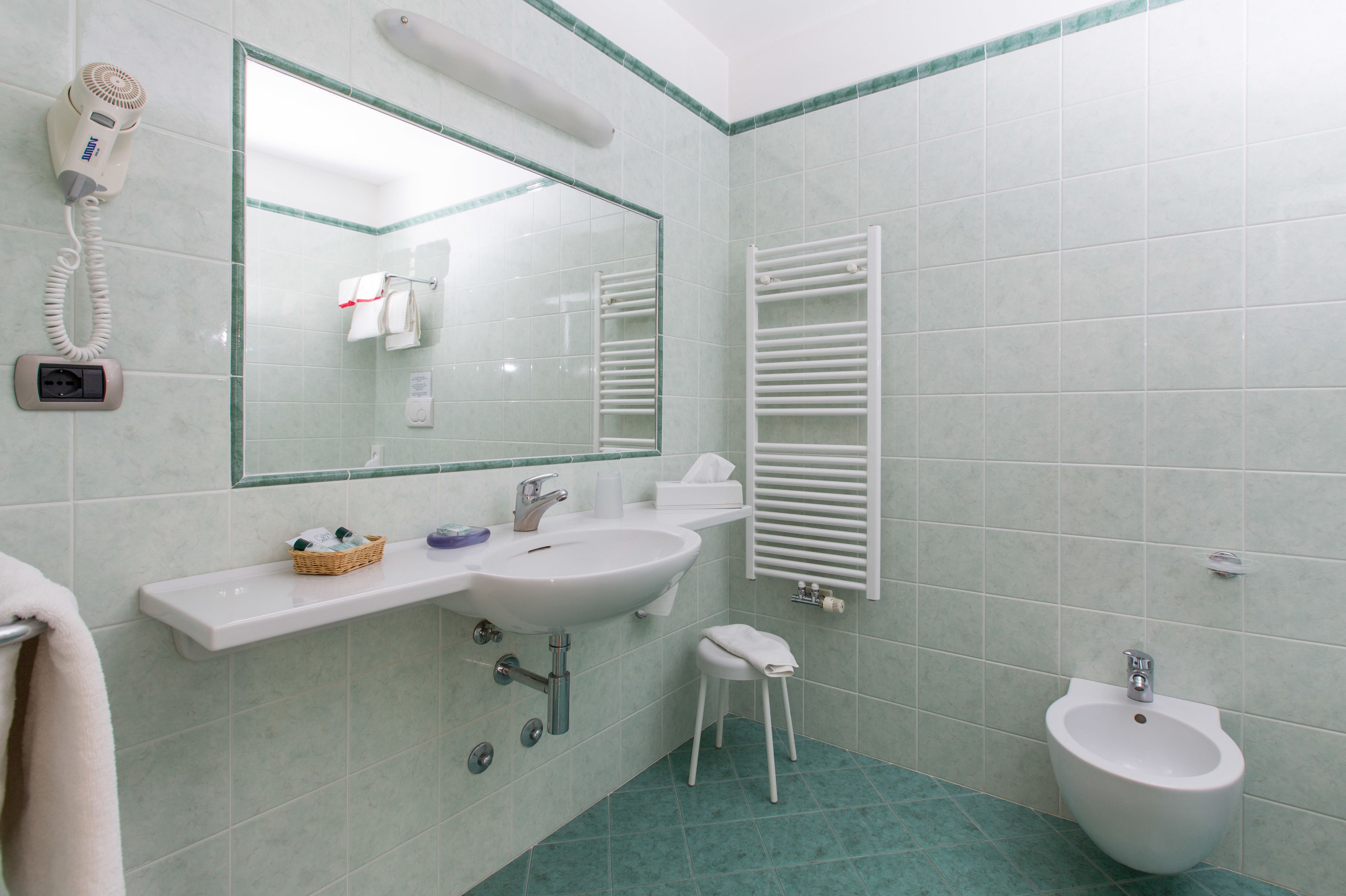 A bathroom with a sink, mirror, towel rack, and bidet.