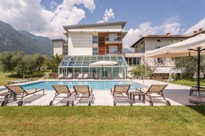 Relax by the pool surrounded by lounge chairs and umbrellas in a scenic mountain setting.