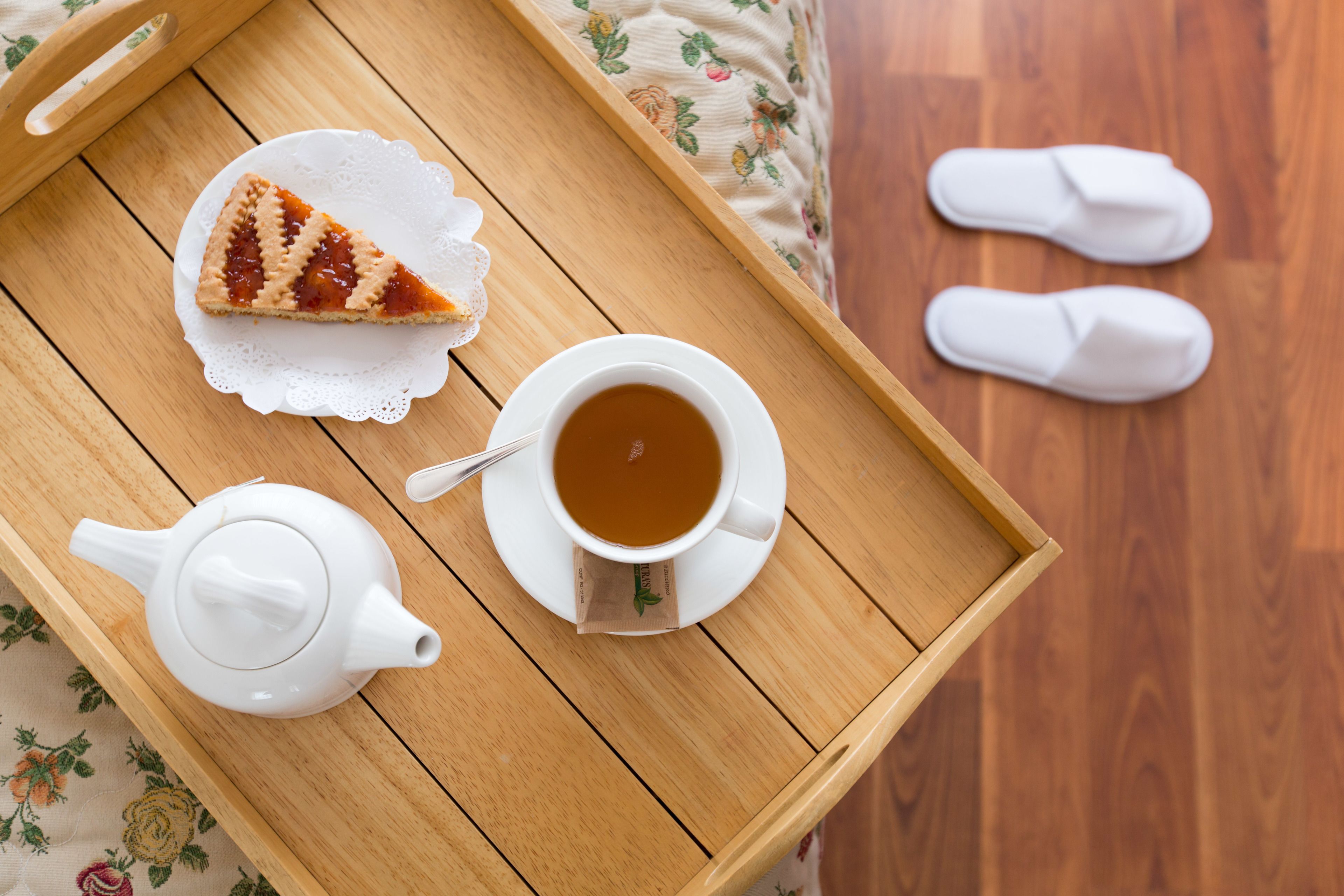 Una bandeja con una rebanada de pastel, una tetera y una taza de té sobre una mesa de madera.