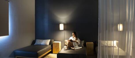 A room with a bed, bedside table, and a reading lamp.