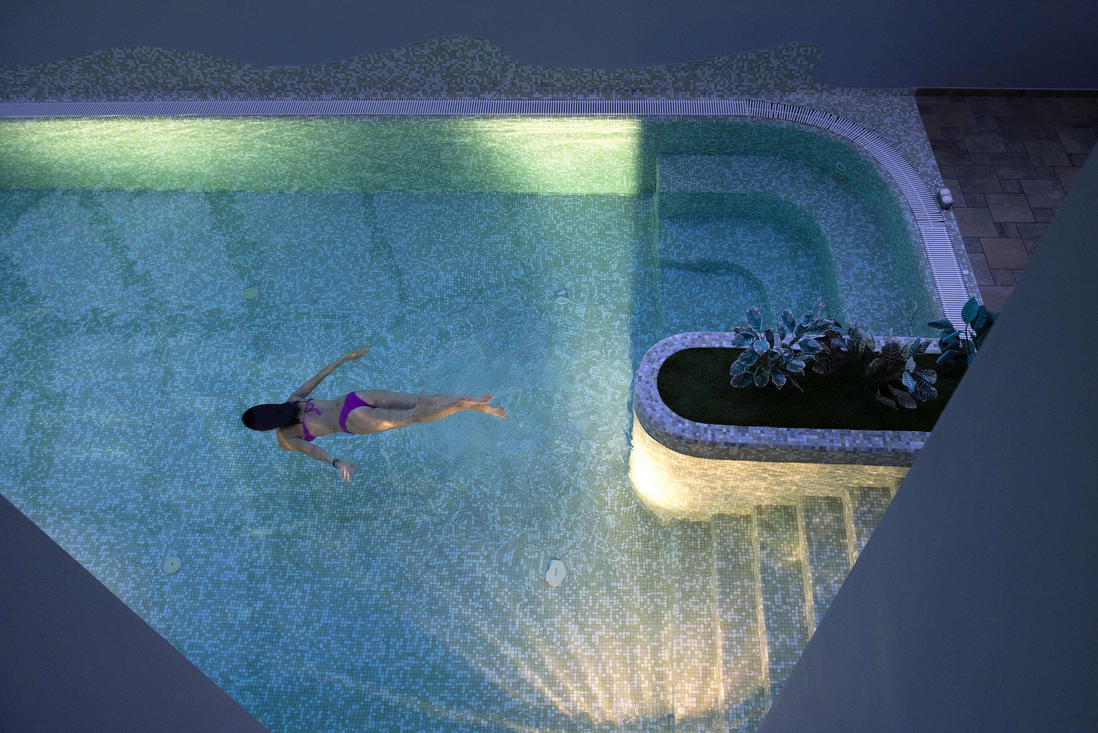 Une piscine dotée d’une terrasse carrelée et d’un petit espace aménagé en jardin.