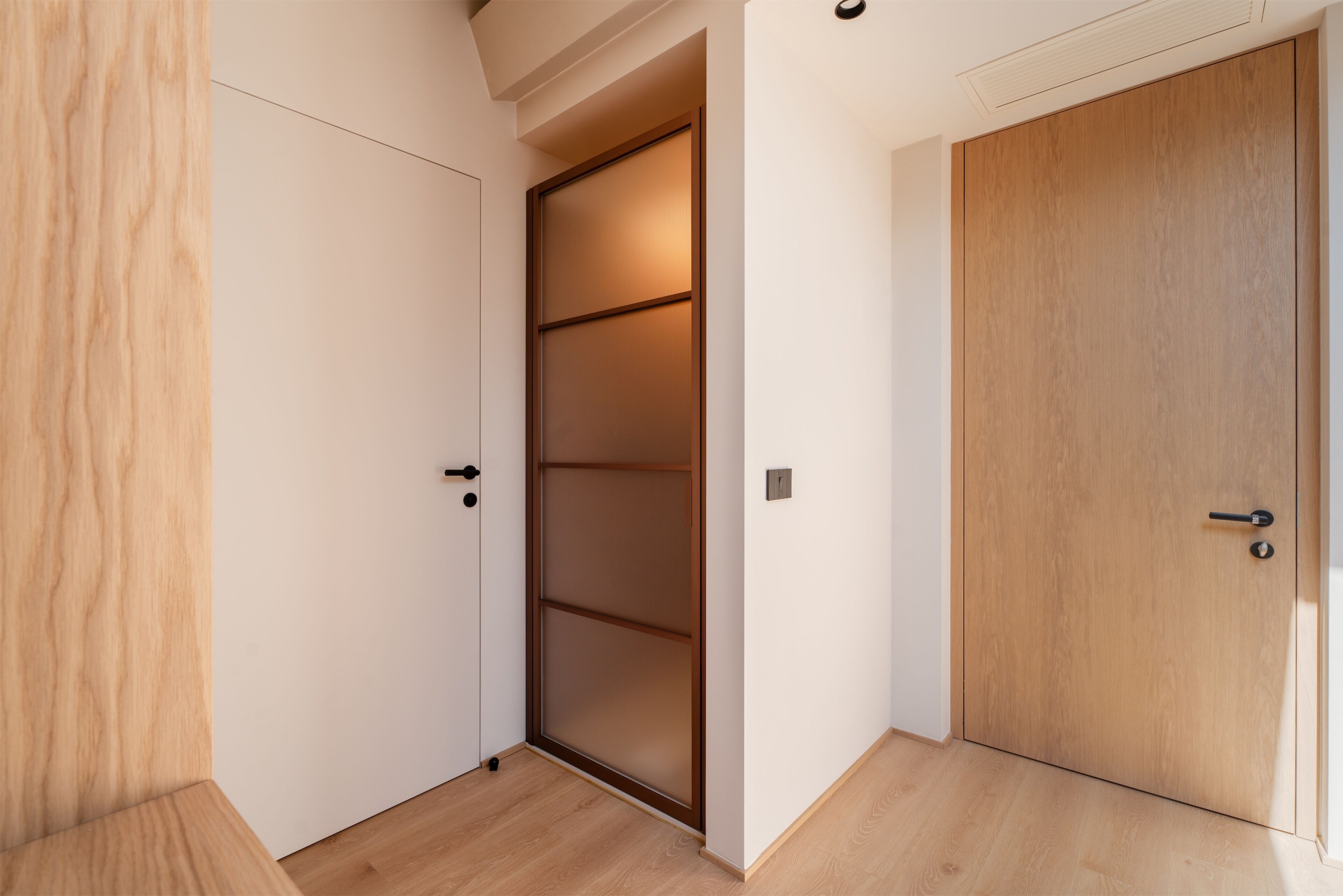 A room with a sliding door, a wooden floor, and a white wall.