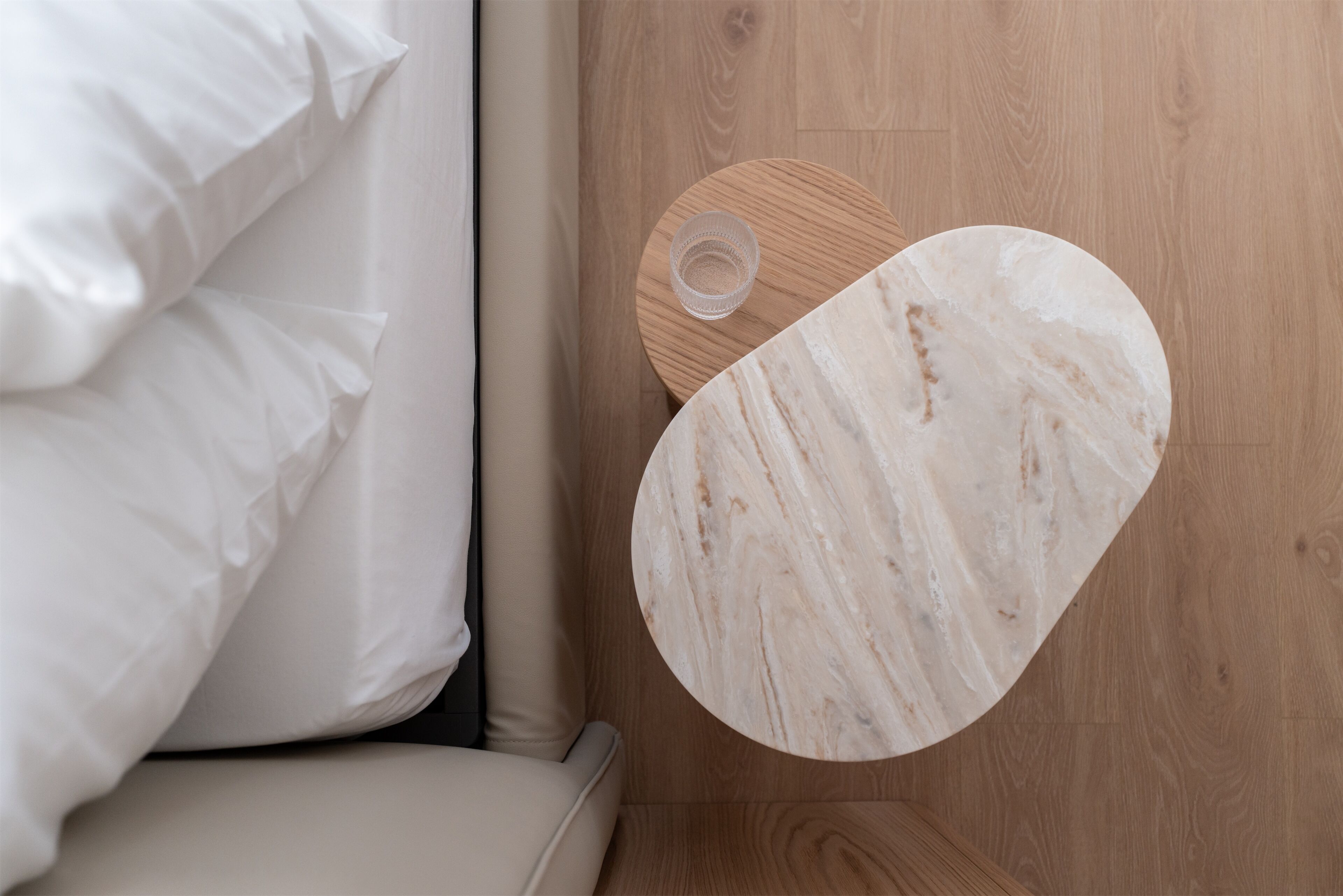 Una camera da letto con un letto, un pavimento in legno e un comodino in marmo.