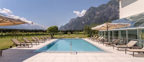 Relax by the serene pool surrounded by lounge chairs and majestic mountains.