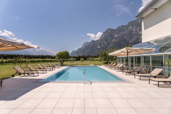 Relax by the serene pool surrounded by lounge chairs and majestic mountains.