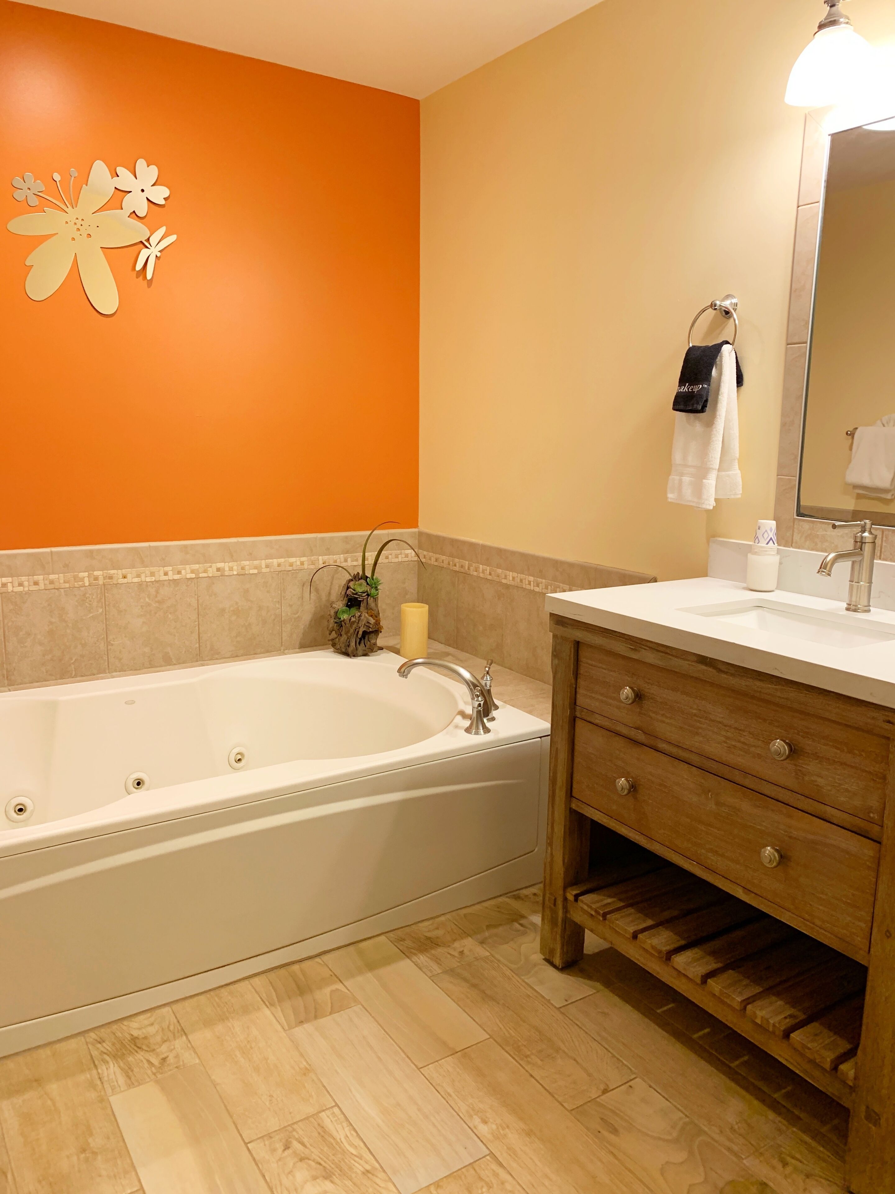 A bathroom with a bathtub, a sink, a mirror, and a towel rack.