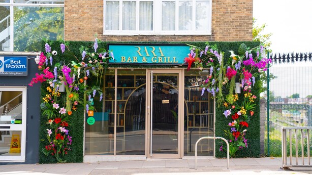 A bar and grill with a green sign, glass doors, and a flower display. -  Best Western Northfields Ealing Hotel-Opposite Northfield Station -Piccadilly line (London)