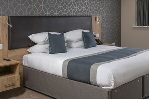 Una camera d'albergo moderna con un letto grande, comodini in legno, una scrivania e una parete decorata con un motivo.