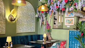 A restaurant interior with a dark wood table, floral chairs, and hanging floral decorations. -  Best Western Northfields Ealing Hotel-Opposite Northfield Station -Piccadilly line (London)