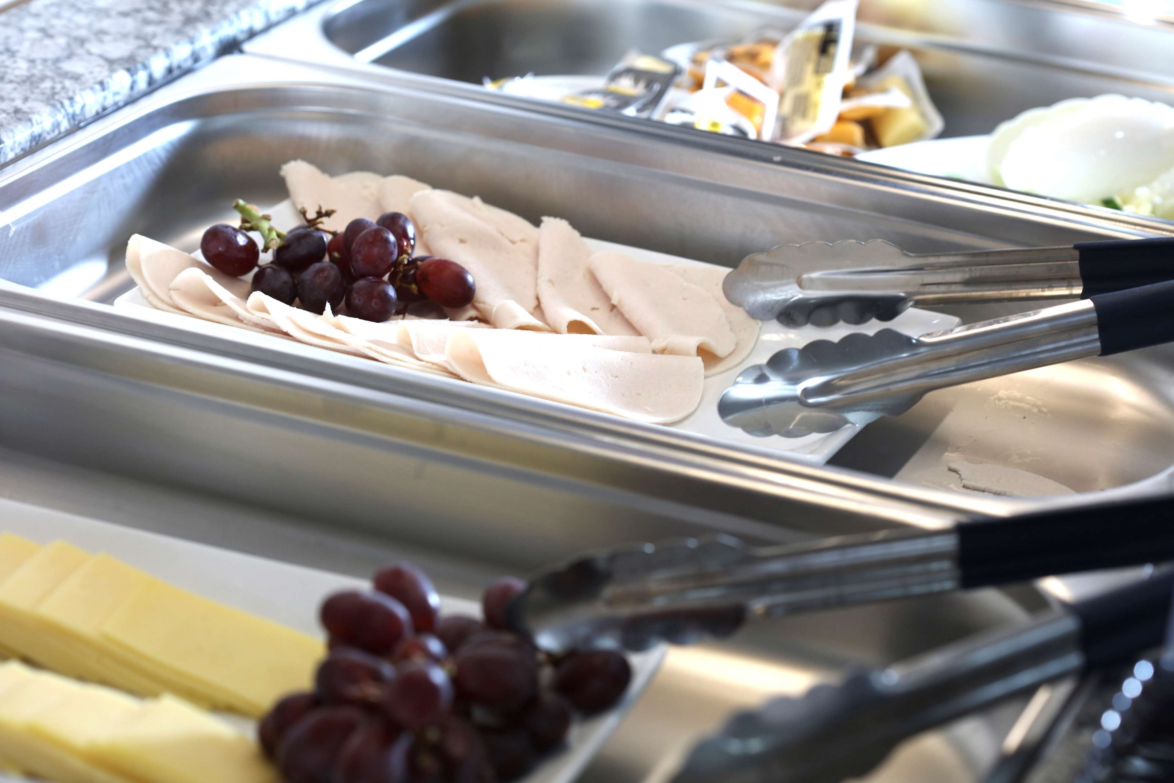 A buffet with various food items including sliced meats, cheese, and grapes.