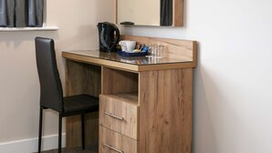 A compact workspace with a wooden desk, a black chair, and a coffee maker. -  Best Western Northfields Ealing Hotel-Opposite Northfield Station -Piccadilly line (London)