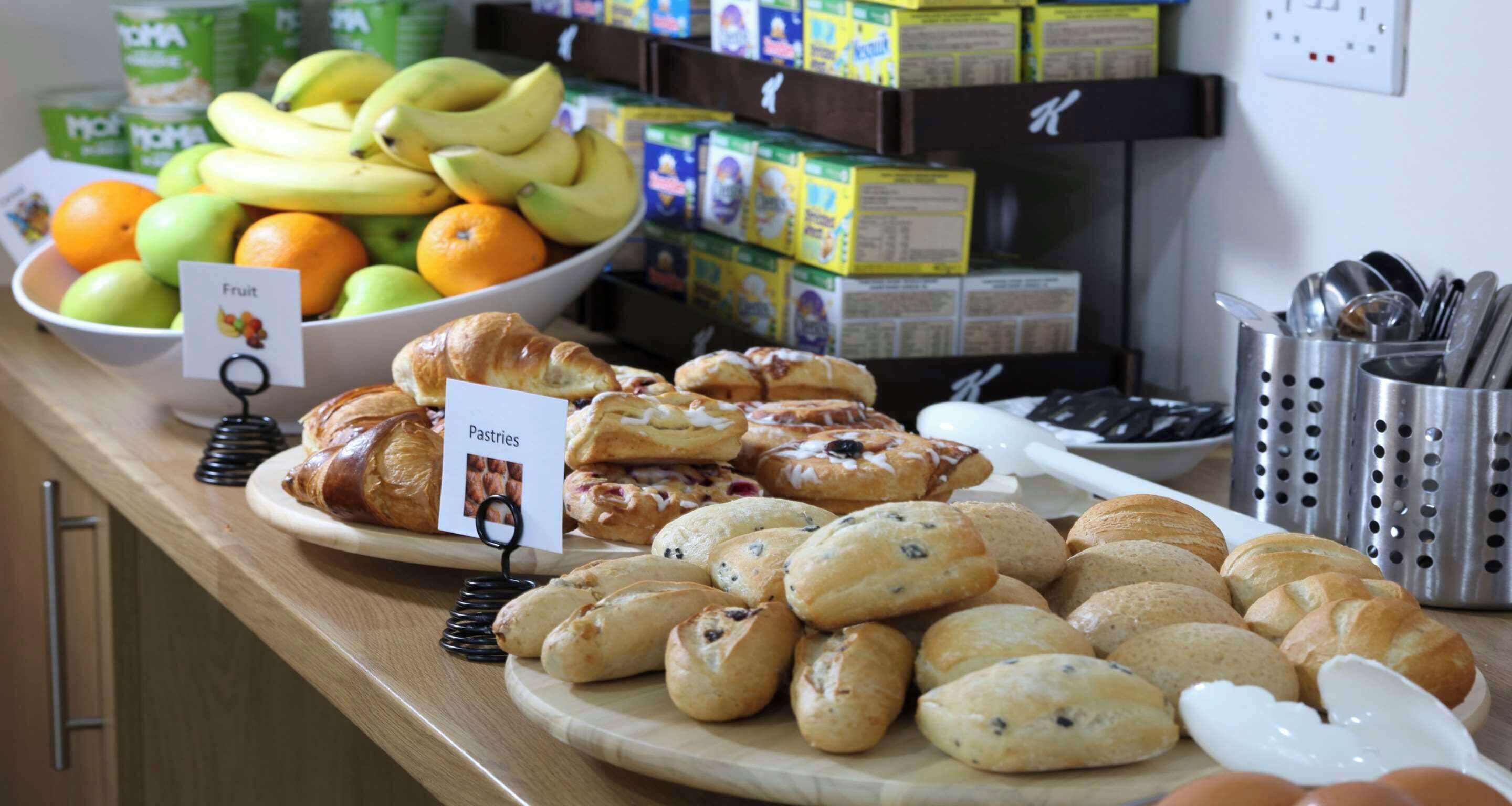 A breakfast buffet with various pastries, fruits, and juice boxes.