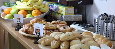 A breakfast buffet with various pastries, fruits, and juice boxes.