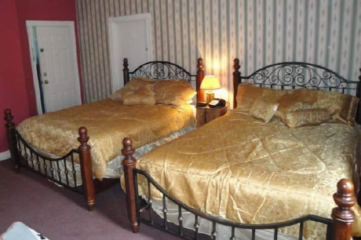 A room with two single beds, a nightstand with a lamp, and a door.