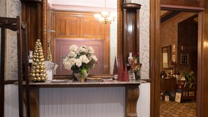 A reception area with a wooden counter, a chandelier, a Christmas tree, and a vase of flowers. - Biltmore Suites Hotel (Baltimore)