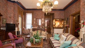 A traditional living room with a chandelier, patterned wallpaper, and a sofa with striped cushions. - Biltmore Suites Hotel (Baltimore)