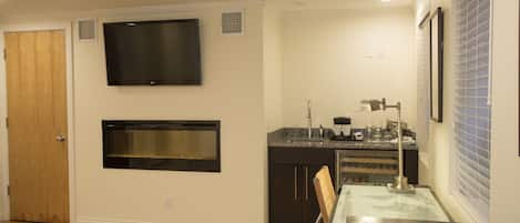 Une cuisine moderne équipée d’un four encastré, d’un four à micro-ondes et d’un téléviseur à écran plat fixé au-dessus du four.