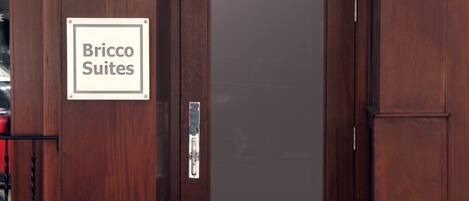 Uma porta de madeira com uma placa que diz 'Brico Suites'.