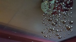 A bar area with stools, a counter with bottles, and a decorative ceiling feature. - Trinity Hotel (Addis Ababa)